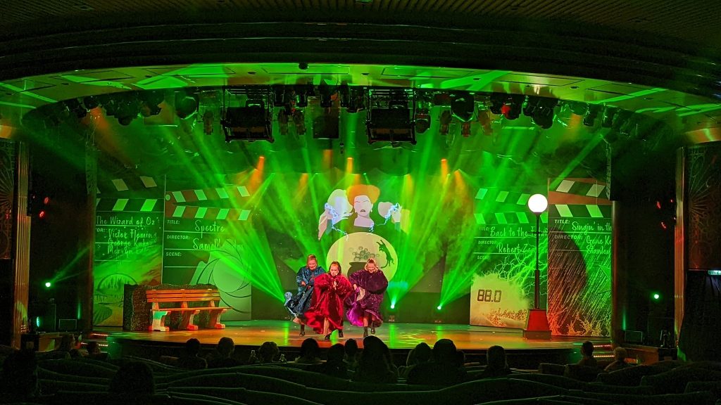Three performers dancing on stage, with green lighting effects behind them.